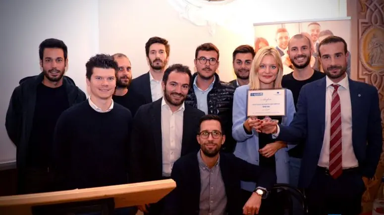 Foto di gruppo dei Giovani Imprenditori del Terziario: una decina di persone in posa, al centro una targa incorniciata