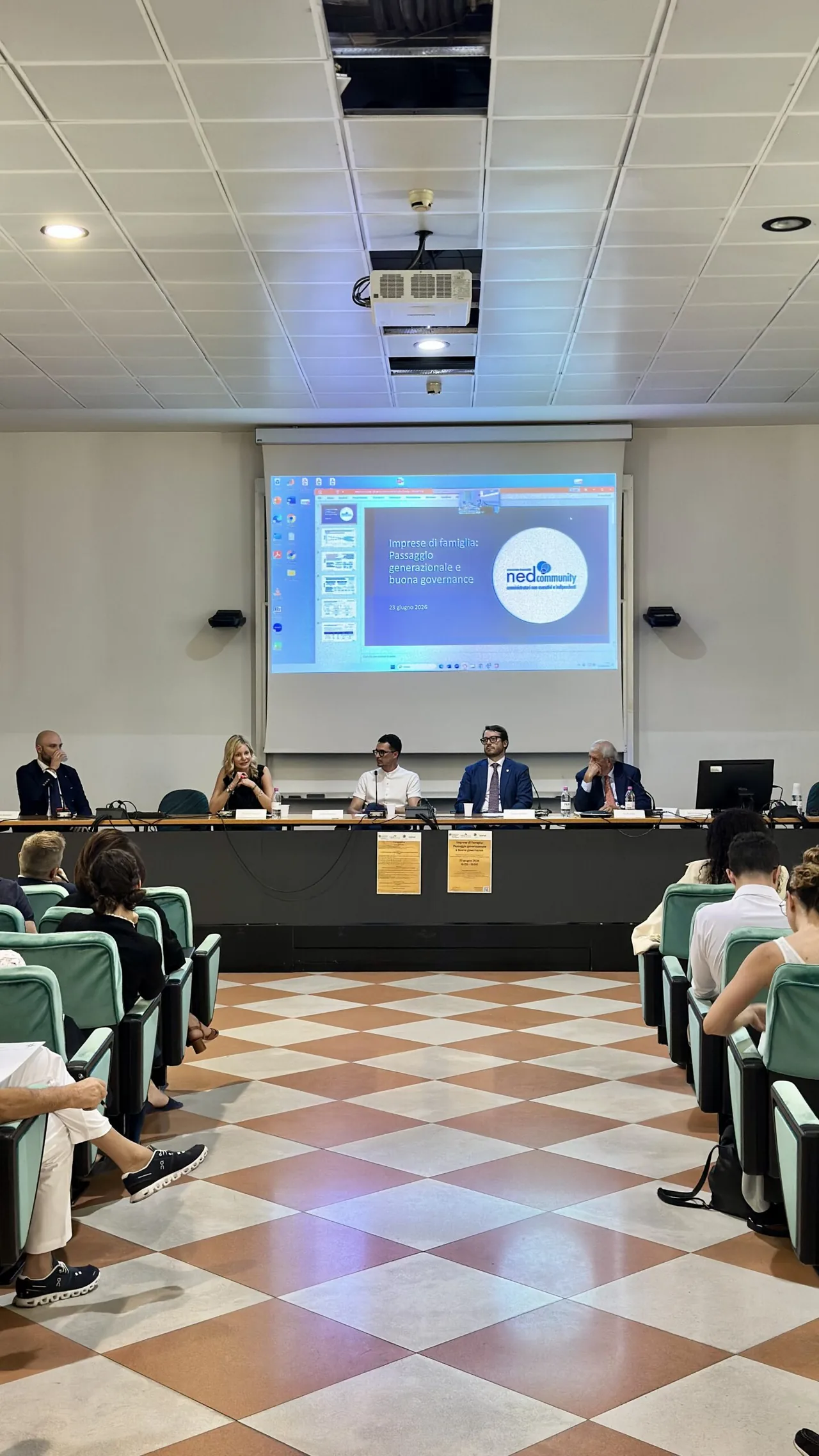La sala conferenze del Palazzo di Economia durante il convegno: i relatori al tavolo, il pubblico in platea e la slide del titolo proiettata sullo schermo
